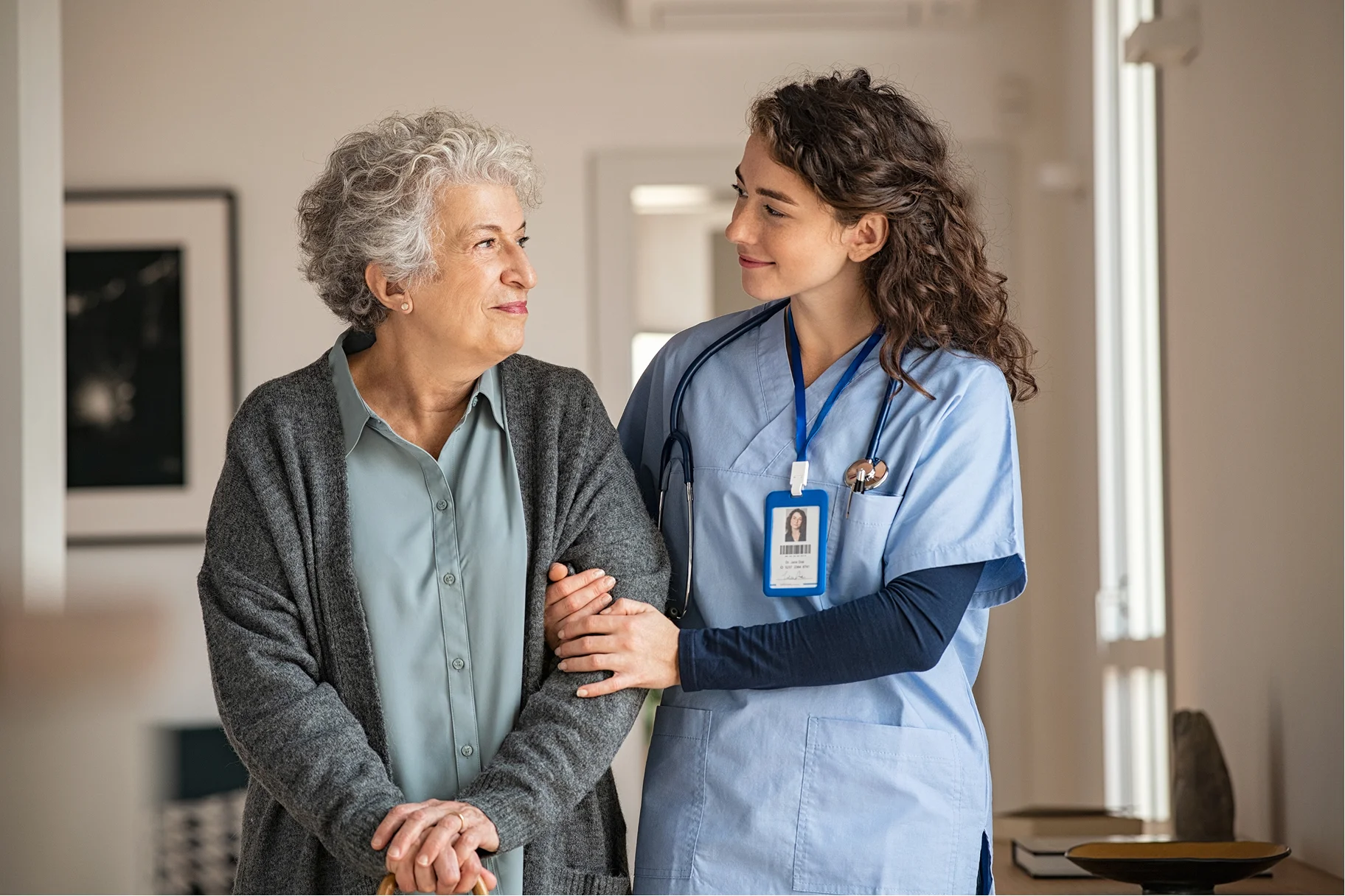 Caregiver supporting an elderly woman with mobility assistance at home